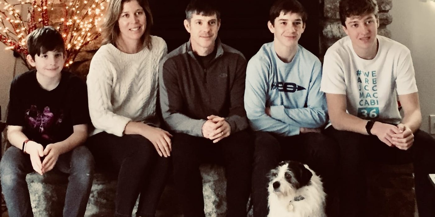 Esther, Mark and their sons by the fireplace with Sochi, the family dog